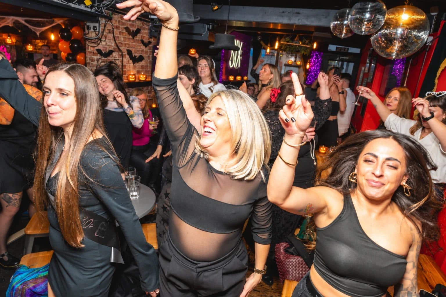 Guests dancing under bats, pumpkins and disco balls at a Halloween drag brunch