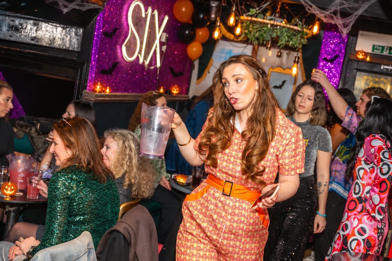 A host in costume with a cocktail jug at the Halloween brunch