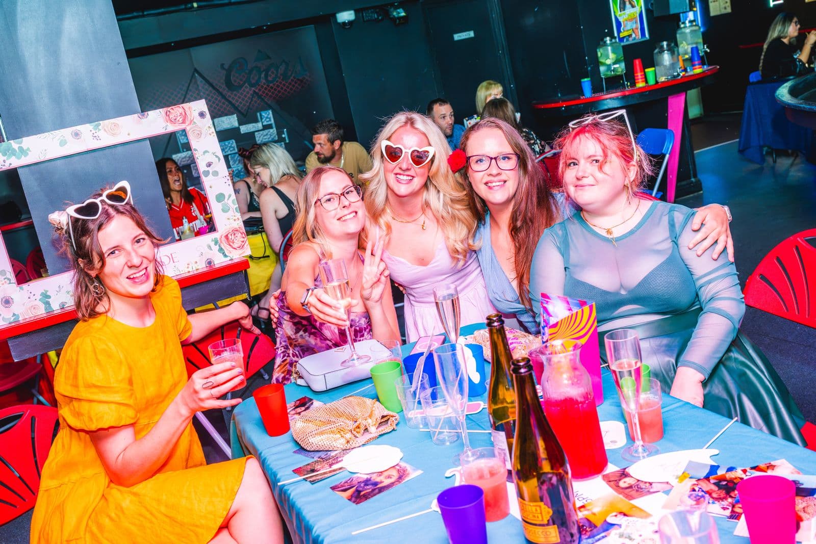 Friends in heart sunglasses toasting with Prosecco at their table