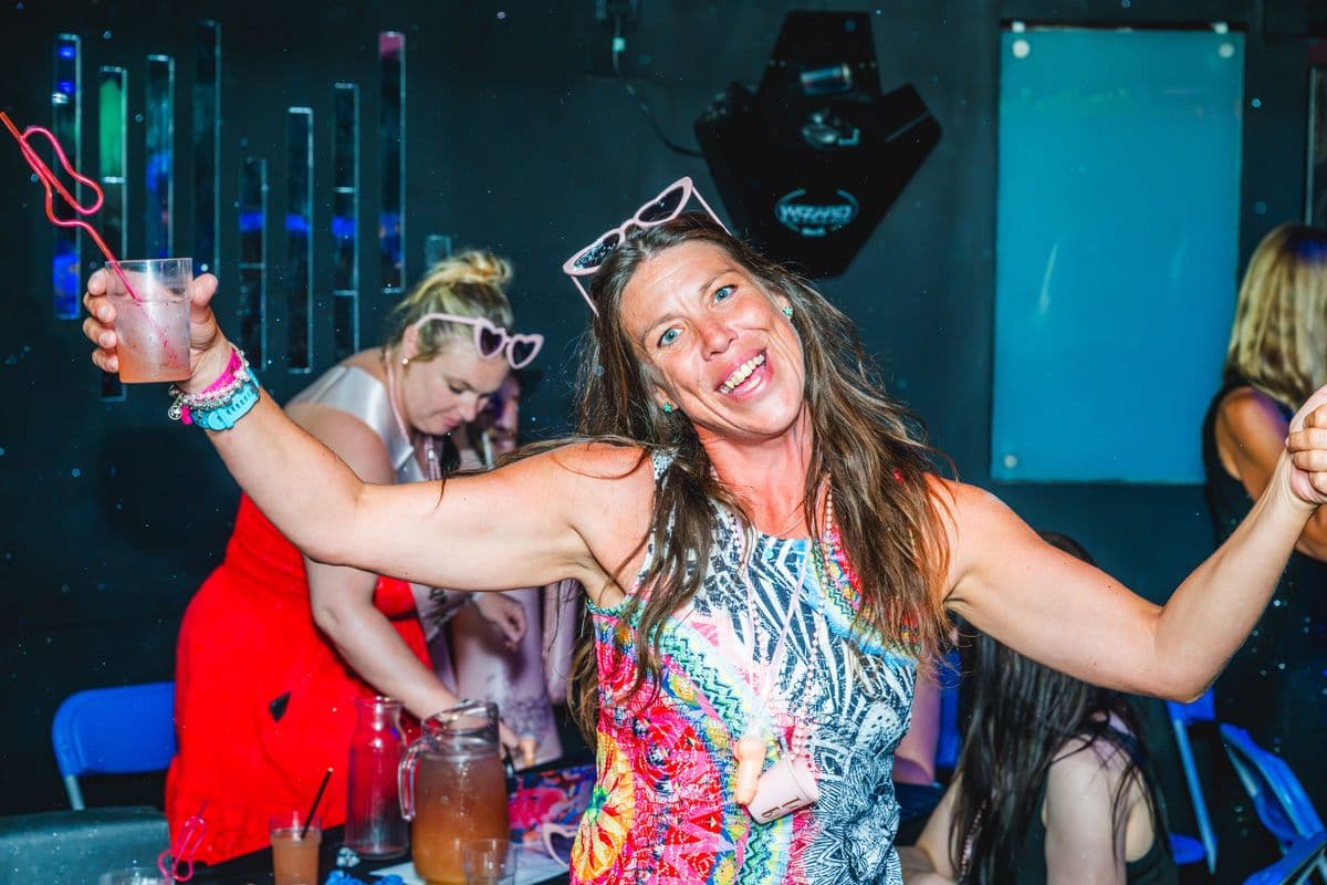 A guest in a bright dress dancing with a drink